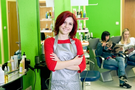 Happy hair salon owner or employee with customers in the background